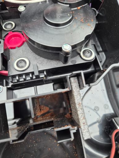 Inneres eines Geräts mit sichtbaren elektrischen Komponenten und Staub.