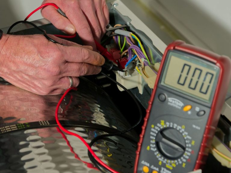 Hände mit Messleitungen verbinden Kabel mit einem Multimeter, das  0 Volt Spannung anzeigt.