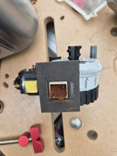 Maschine mit grauem Gehäuse, einer quadratischen Öffnung und sichtbarem Motor.