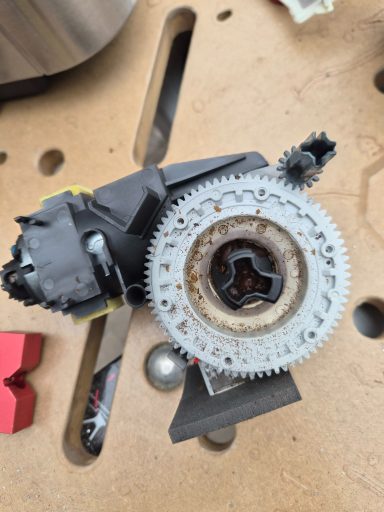 Motor mit Zahnrad und Zahnrädern auf einer Werkbank, teilweise rostig und abgenutzt.